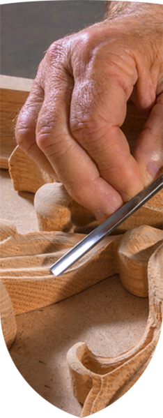Person carving wood with chisel, demonstrating the art of wood carving
