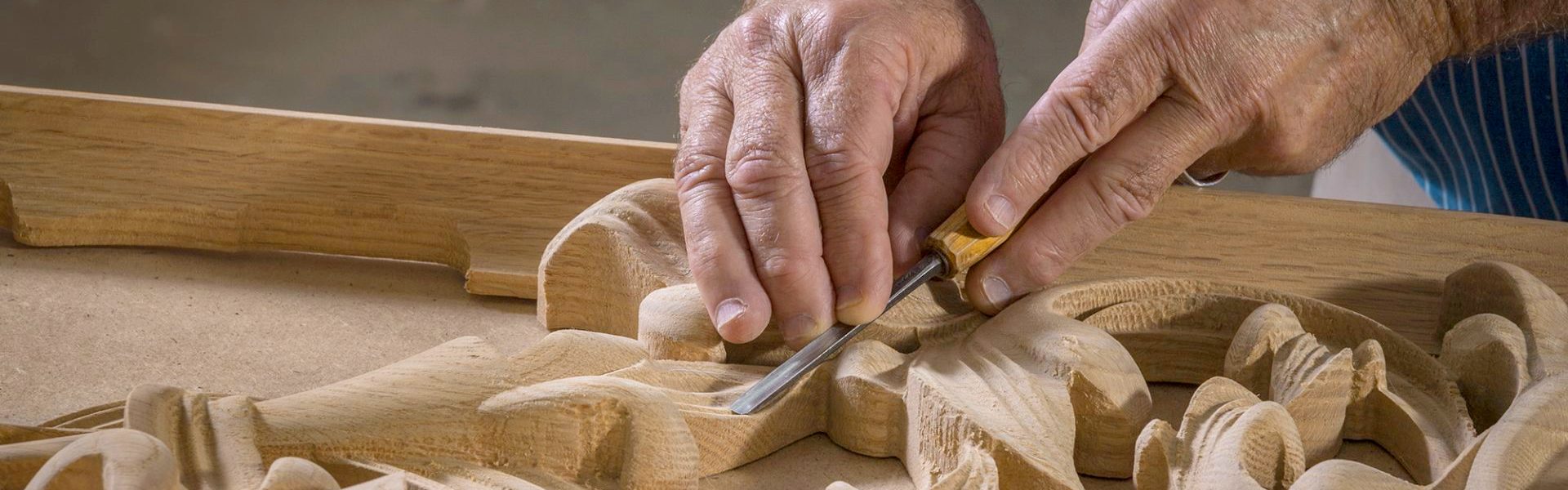 Person carving wood with a chisel to create decorative designs