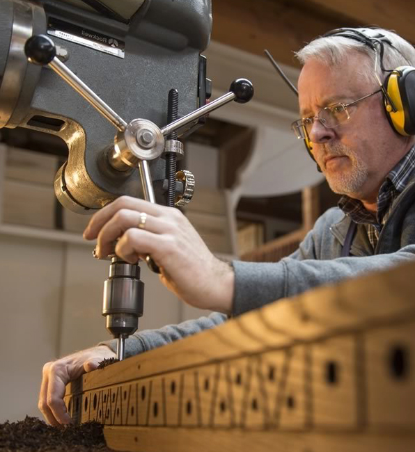 Person using a drill press to drill holes into a piece of wood